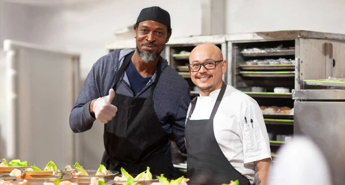 Two cooks smiling in a kitchen